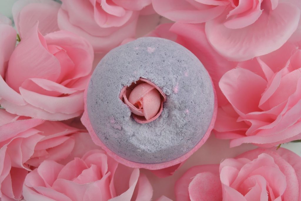 Sex Bomb Bath Bomb by Lush amidst pink plastic flowers (view from top)