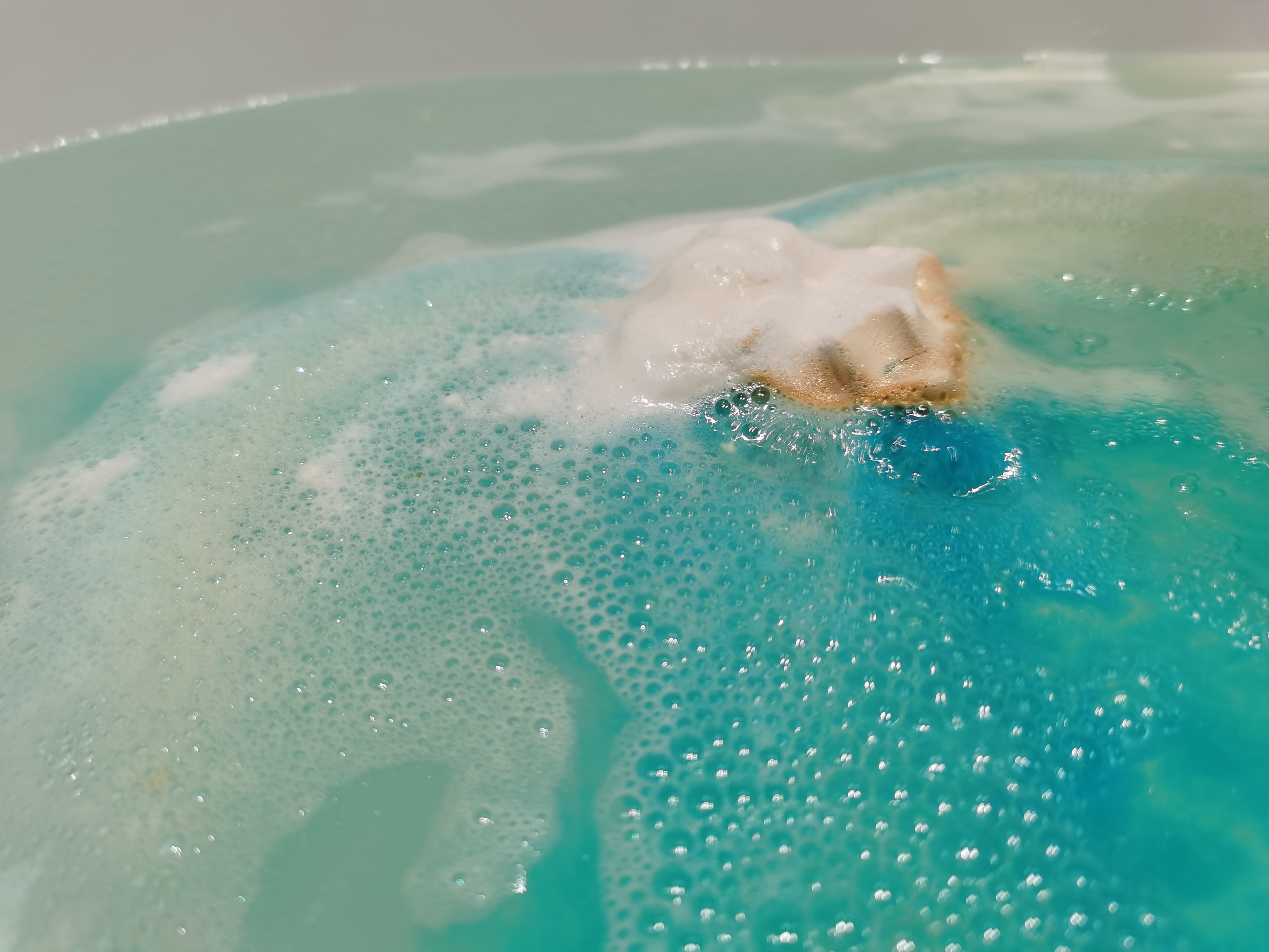 Golden Wonder Bath Bomb by Lush dissolving into blue water