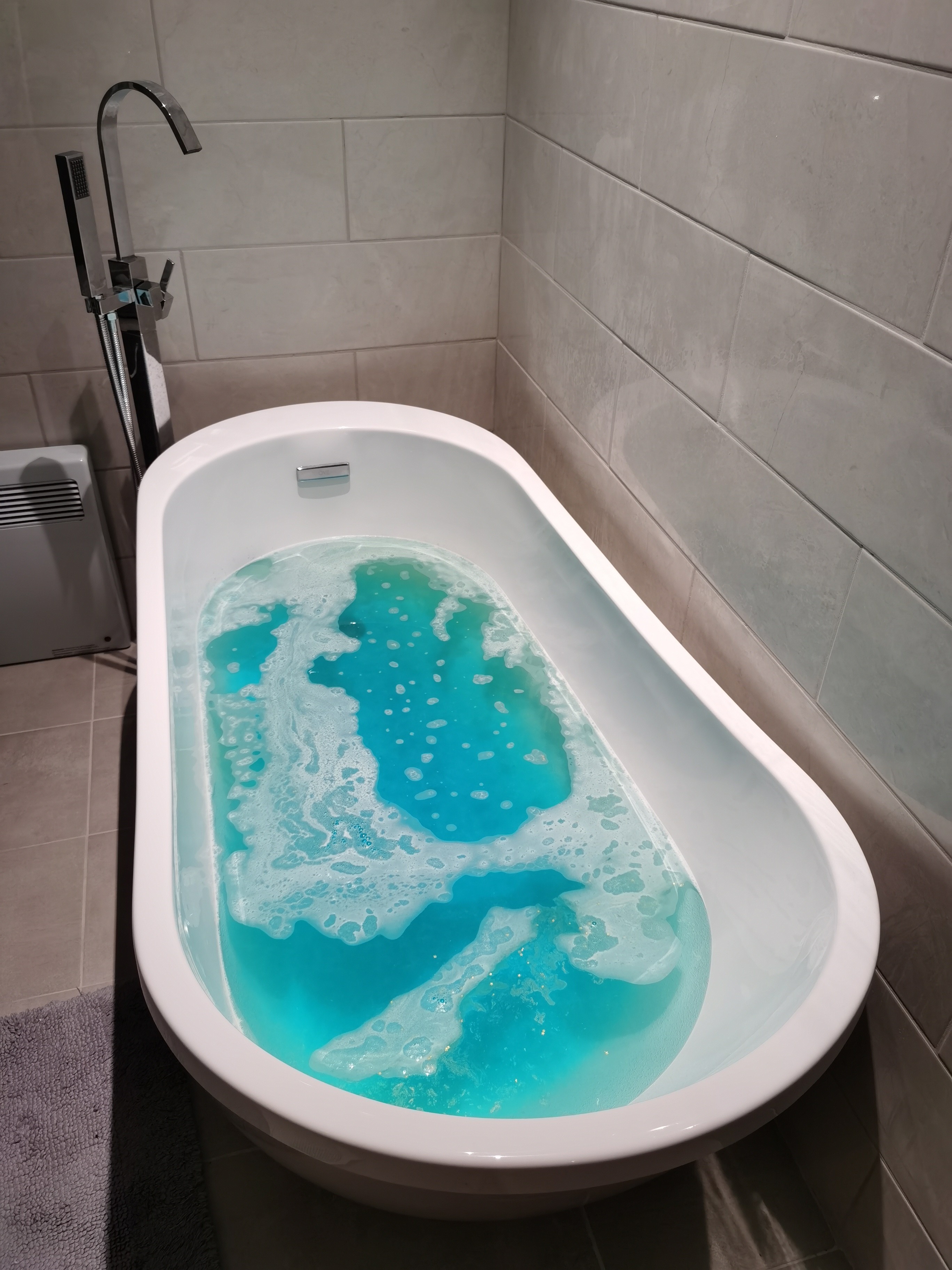 Golden Wonder Bath Bomb by Lush fully dissolved in a white bath tub