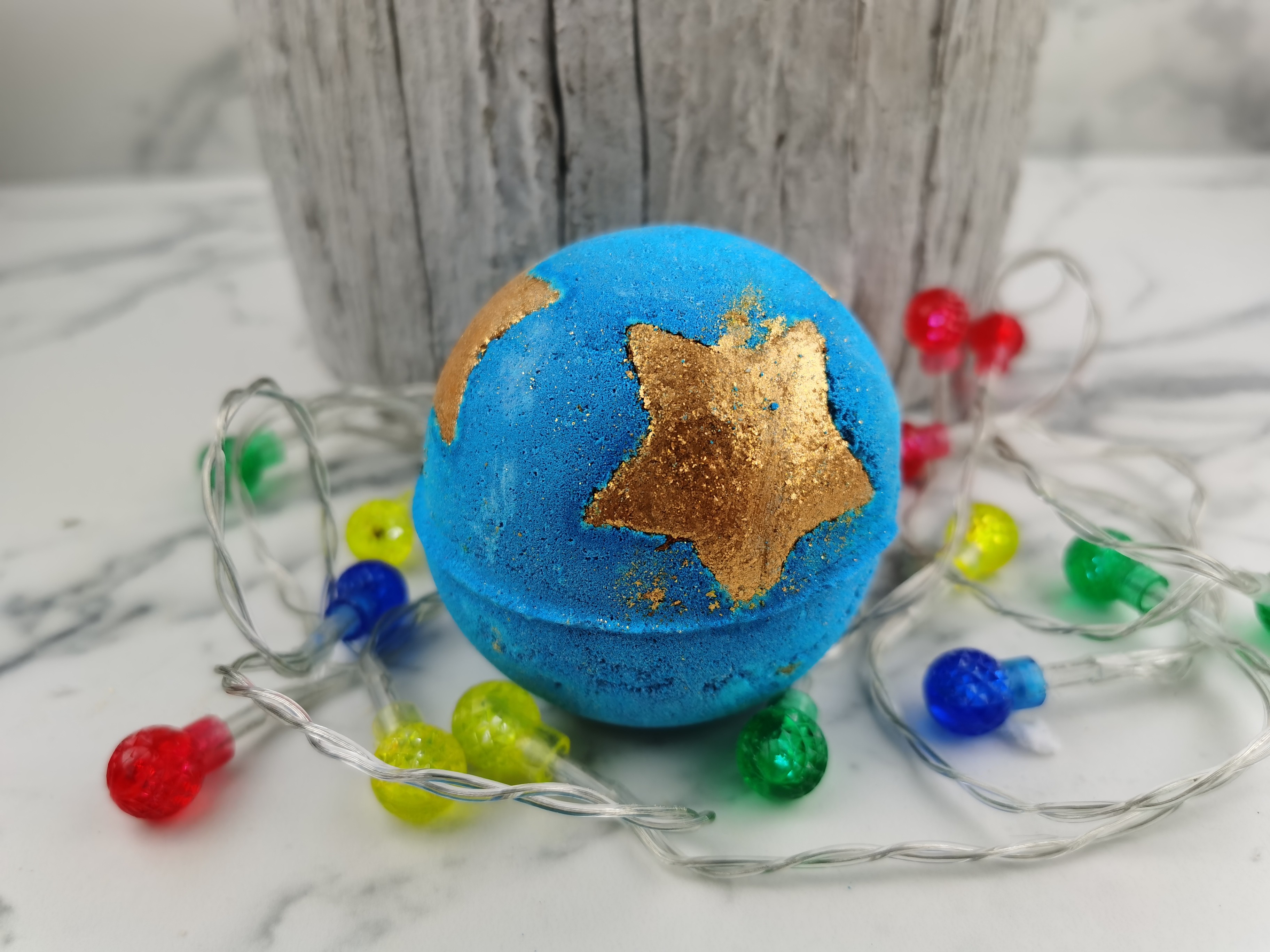 Shoot for the star bath bomb with christmas lights on a marbled table with wood nearby