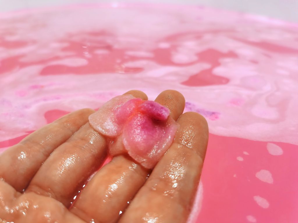 Sex Bomb Bath Bomb rose in hand above pink rosewater