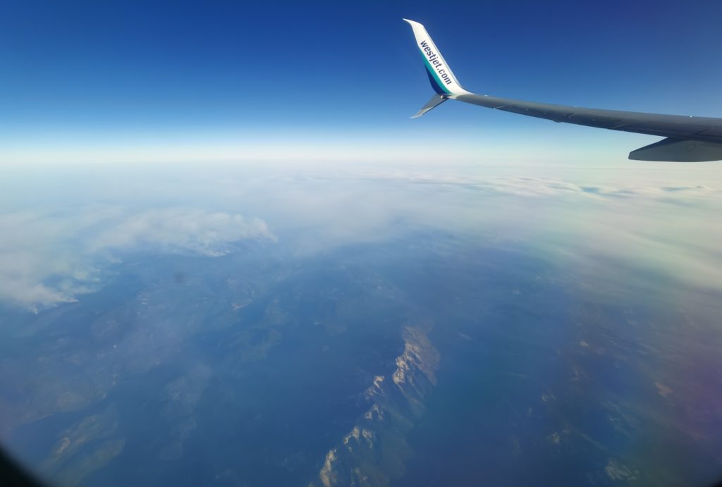Westjet airplane wing in the sky over Canadian mountains