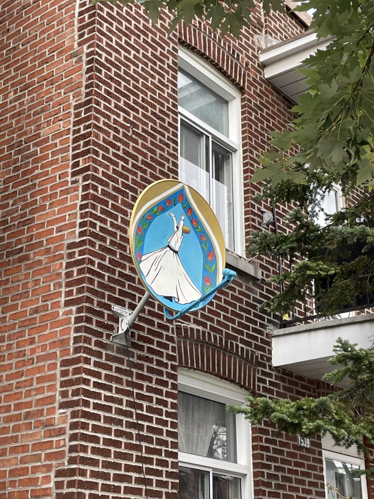 Satellite dish on the side of a house with a beautiful blue painting