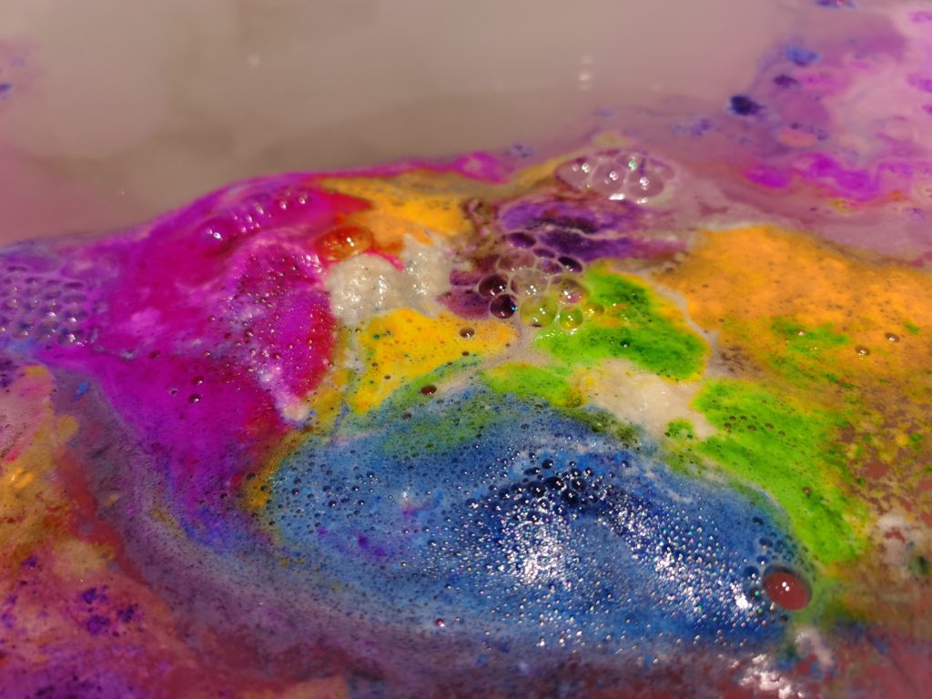 colorful embeds on top of water from classic train bath bomb