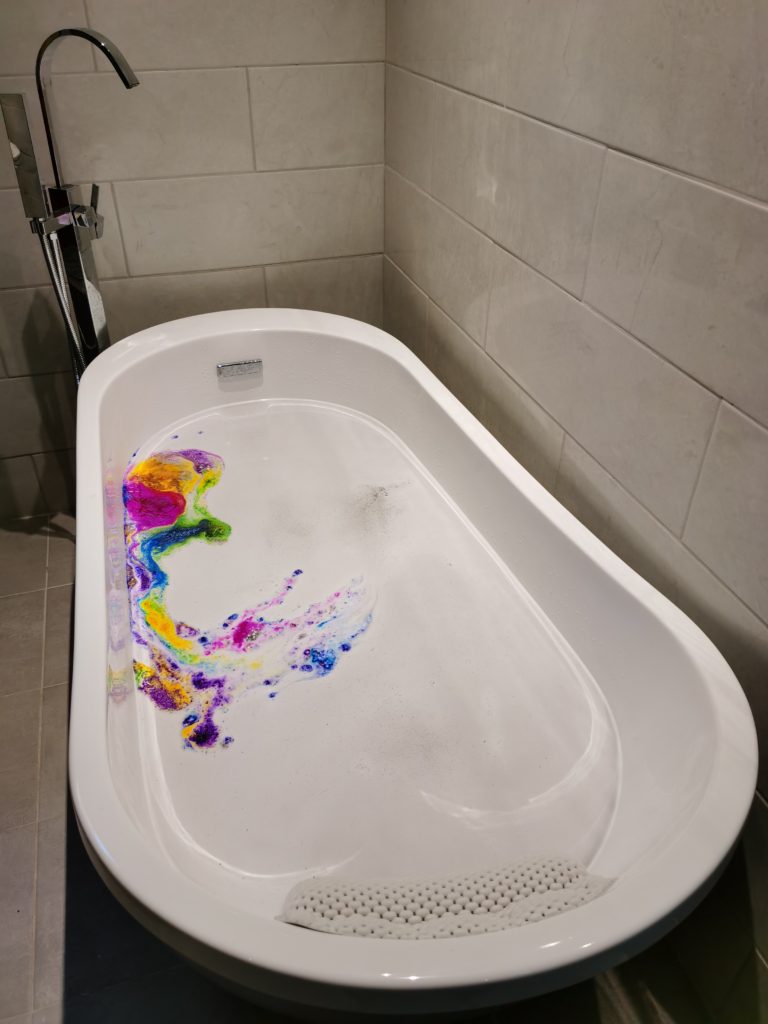 colorful embeds on top of water in bath tub from classic train bath bomb